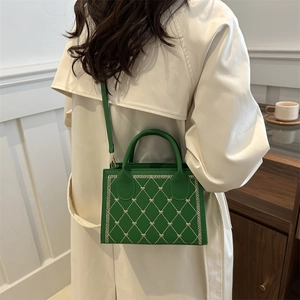 Sac sous le bras en cuir vert matelassé avec broderies de cœurs sur un mannequin