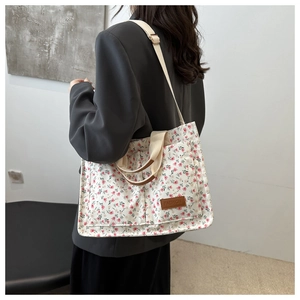 Detail of floral canvas tote bag featuring a leather fashion patch and dual pockets