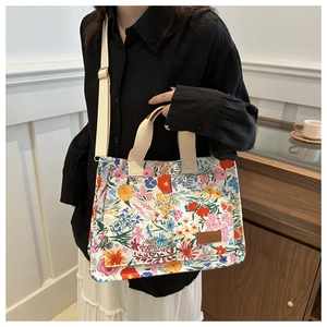 Detail of floral canvas tote bag showing side pocket, leather label and adjustable strap