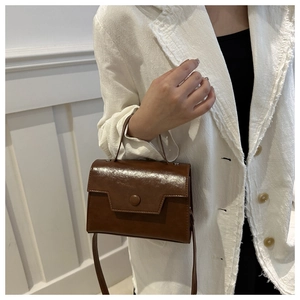 Gros plan du petit sac carré en cuir marron brillant avec boucle circulaire vintage