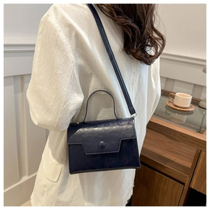 Vue détaillée d'un sac rétro bleu marine avec des bandoulières réglables et une poignée chic