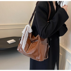 Detail of dark brown leather tote with decorative white lace scarf on the shoulder strap