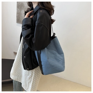 Détail du grand sac seau en toile denim avec garnitures en cuir contrastées et anneaux métal