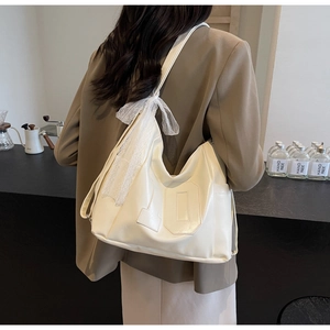 Detail of a large cream white hobo bag with a lace bow and number ten stitching