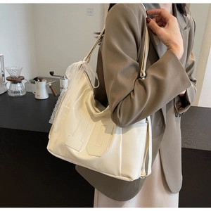 Detail of minimalist cream tote bag with number ten stitching and lace bow decoration