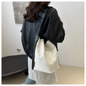 Vue détaillée du dos d'un sac seau en toile blanche avec des anses en cuir noir