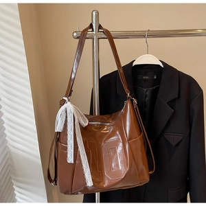 Detailed view of brown tote bag with number 10 embossing and white lace bow decoration