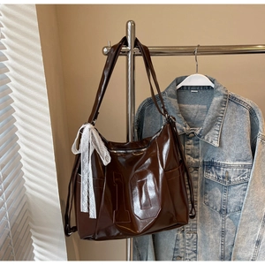 Detail view of large brown patent leather tote with number 10 embossing and lace bow