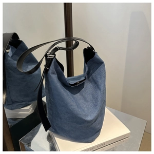 Detail der blauen Denim-Beuteltasche mit schwarzem Lederriemen und silberner Metallschnalle