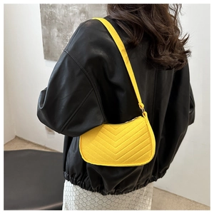 Detail of bright yellow crescent shoulder bag with V-shaped quilting on black jacket