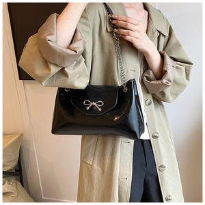 Détail du sac croissant noir brillant avec nœud en argent et bandoulière chaîne