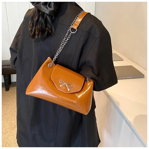 Détail d'un sac bandoulière marron en cuir avec nœud argenté porté par un mannequin