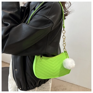 Dettaglio borsa a spalla trapuntata verde neon con catena dorata e pompon bianco