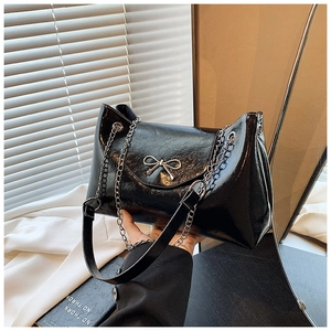 Détail du sac bandoulière en cuir verni noir brillant avec nœud métallique argenté