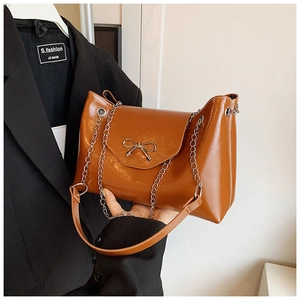Détail du sac marron caramel brillant avec boucle nœud dorée et bandoulière
