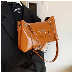 Détail du sac bandoulière marron ambre avec nœud métallique argenté et cuir texturé