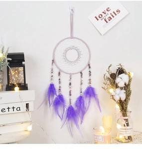 Detail of dream catcher with purple feathers, natural gravel beads and woven design