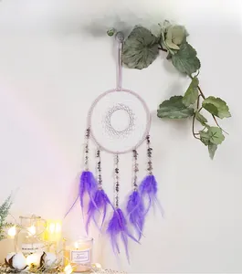 Detailed view of handmade purple dreamcatcher with natural stones and soft feathers