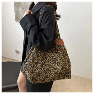 Detailed view of leopard print tote bag with brown leather accents worn by model