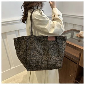 Close-up of leopard print canvas tote bag with pink leather label and metal studs detail