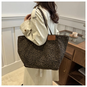 Detailed close-up of a large leopard print canvas tote bag with outer pocket and leather patch