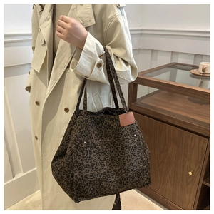 Detail of leopard print tote bag featuring pink leather tag and metal rivets on side pocket