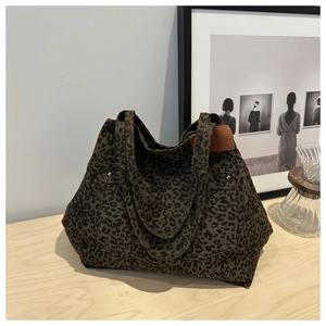 Detailed view of leopard print canvas tote bag with brown leather tag and silver rivets