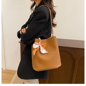 Sac seau en cuir marron avec détail de foulard en soie décoratif dans un intérieur cosy