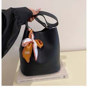 Détail du sac seau en cuir noir avec foulard décoratif et marquage mode élégant