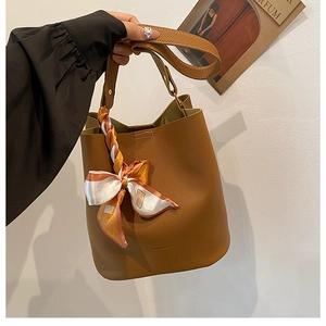 Gros plan d'un sac seau en cuir marron avec nœud en soie et lettrage doré