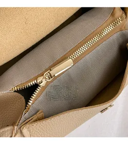 Detail of beige lychee leather crossbody bag with golden zipper and herringbone lining