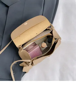 Detail view of khaki crossbody bag interior showing storage space for perfumes and cosmetics