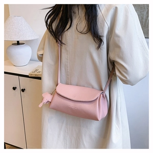 Detail view of pink leather crossbody bag with cute elephant charm on model in home setting