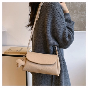 Detail of beige lychee pattern leather crossbody bag with a small elephant charm