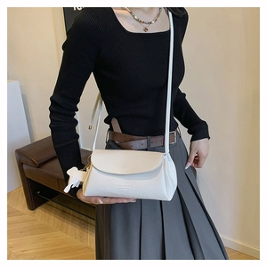 Close-up of white pebble leather crossbody bag featuring a cute elephant charm