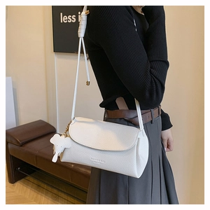Detail of white lychee texture shoulder bag with envelope flap and elephant charm