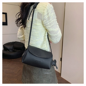 Close-up of black lychee grain leather shoulder bag worn by model in a cozy setting