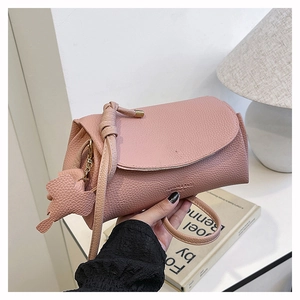 Detail of pink lychee grain leather handbag with matching leaf charm and magnetic flap closure