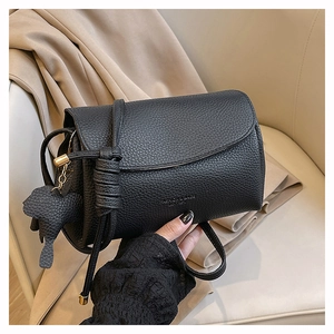 Detail of black pebbled leather crossbody bag with knot strap and elephant charm