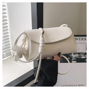 Close-up of white lychee pattern leather crossbody bag with elephant charm and logo