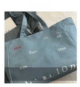 Close-up of vintage denim tote bag featuring minimalist fashion typography and daily schedule