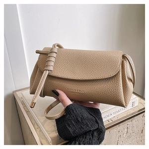 Close-up of beige lychee grain leather bag with knotted strap and metal tip detail