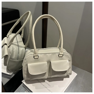 Close-up of cream white patent leather handbag with dual front pockets and silver hardware