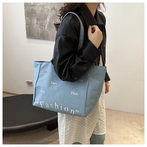 Detailed side view of a large denim tote bag worn on shoulder with fashion print