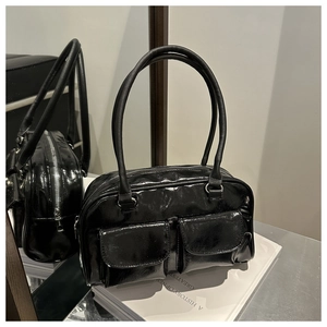 Detail of glossy black faux leather handbag featuring dual front pockets and silver hardware