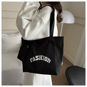 Détail du sac cabas en toile noire avec imprimé fashion et mini pochette à bandoulière