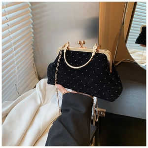 Detail of vintage black velvet shell bag with pearl accents and gold metal handle