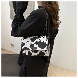 Detail of trendy cow print square crossbody bag with stylish silver metal chain strap