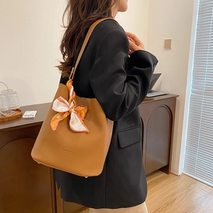 Sac seau en cuir marron avec foulard en soie imprimé sur la anse porté par mannequin