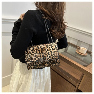 Detail of leopard print flap bag with metal chain strap and vintage clasp in a lifestyle setting